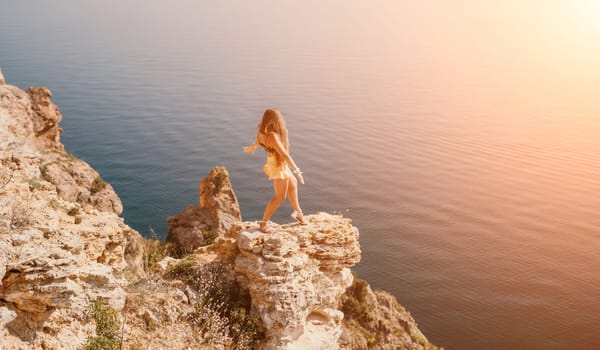 Woman travel sea. Happy tourist taking picture outdoors for memories. Woman traveler looks at the edge of the cliff on the sea bay of mountains, sharing travel adventure journey.