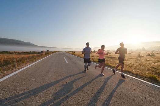 A group of friends, athletes, and joggers embrace the early morning hours as they run through the misty dawn, energized by the rising sun and surrounded by the tranquil beauty of nature.