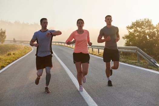 A group of friends, athletes, and joggers embrace the early morning hours as they run through the misty dawn, energized by the rising sun and surrounded by the tranquil beauty of nature.