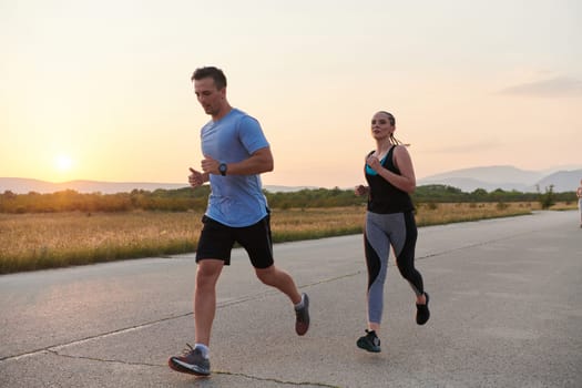 A vibrant couple dashes running the outdoors, embodying the essence of athleticism and romance, their confident strides reflecting a shared commitment to fitness and preparation for future marathon challenges.