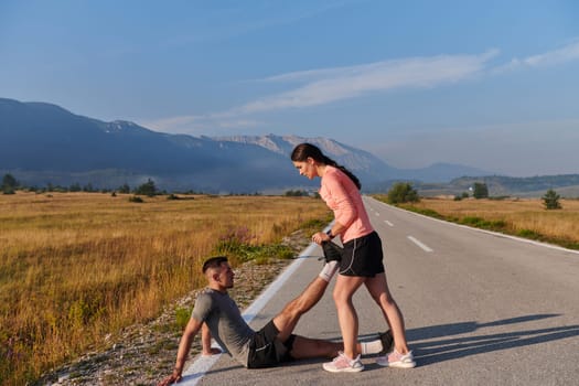 As dawn breaks, a romantic couple engages in a gentle stretch together, symbolizing their shared dedication and preparation for an invigorating early morning run.