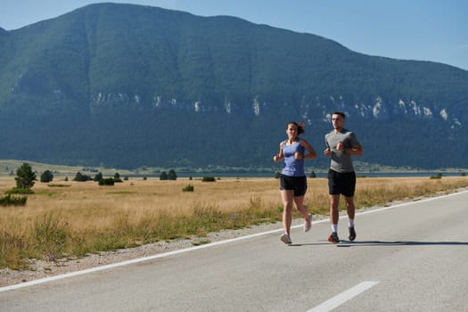 A couple runs through a sun-dappled road, their bodies strong and healthy, their love for each other and the outdoors evident in every stride.