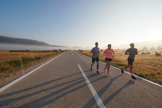 A group of friends, athletes, and joggers embrace the early morning hours as they run through the misty dawn, energized by the rising sun and surrounded by the tranquil beauty of nature.