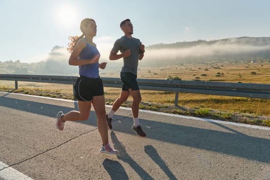 A couple runs through a sun-dappled road, their bodies strong and healthy, their love for each other and the outdoors evident in every stride.