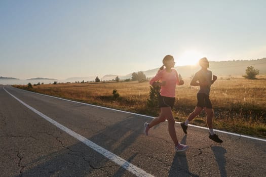 A couple runs through a sun-dappled road, their bodies strong and healthy, their love for each other and the outdoors evident in every stride.