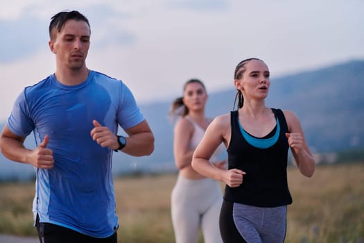 A diverse group of runners finds motivation and inspiration in each other as they train together for an upcoming competition, set against a breathtaking sunset backdrop.