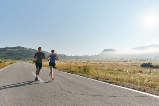 A couple runs through a sun-dappled road, their bodies strong and healthy, their love for each other and the outdoors evident in every stride.