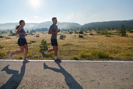 A couple runs through a sun-dappled road, their bodies strong and healthy, their love for each other and the outdoors evident in every stride.