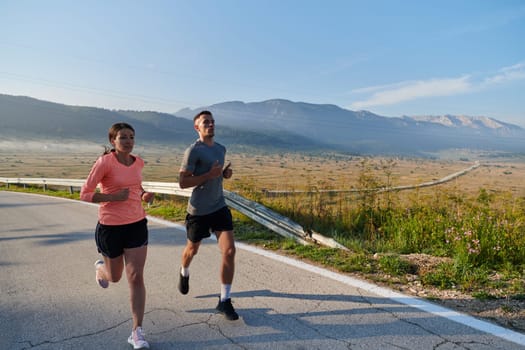 A couple runs through a sun-dappled road, their bodies strong and healthy, their love for each other and the outdoors evident in every stride.