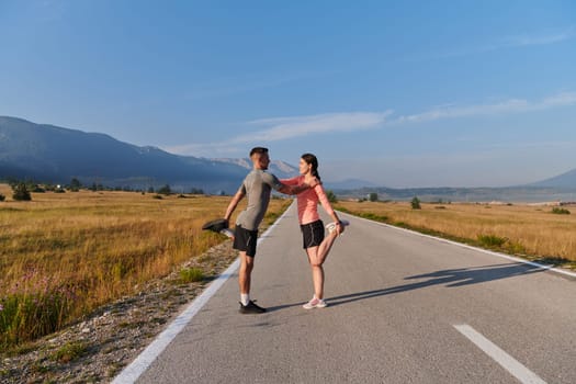 As dawn breaks, a romantic couple engages in a gentle stretch together, symbolizing their shared dedication and preparation for an invigorating early morning run.