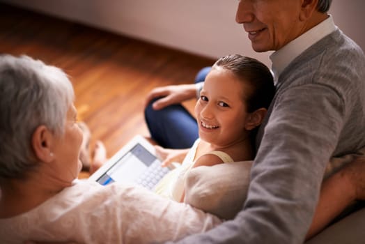 Child, grandparents and tablet on couch in home or online game or communication, teaching or connection. Elderly couple, retirement and girl or internet learning in apartment, development or bonding.