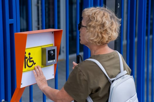 An elderly blind woman reading a text in braille. Button for calling help for people with disabilities