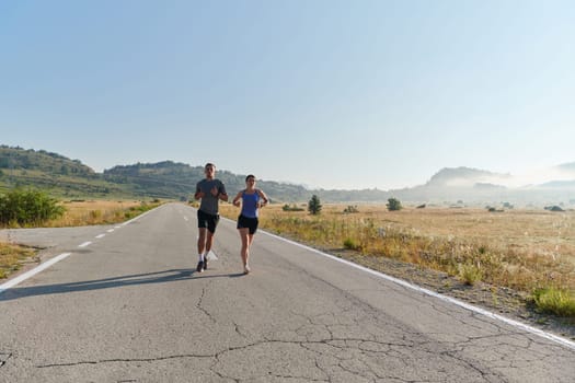 A couple runs through a sun-dappled road, their bodies strong and healthy, their love for each other and the outdoors evident in every stride.