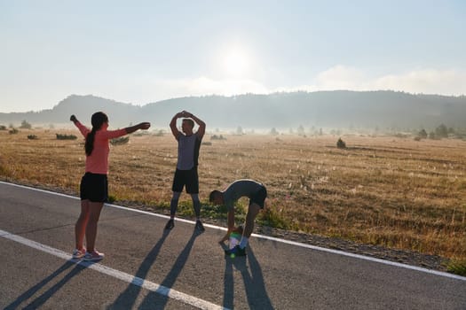 A vibrant and diverse group of athletes engage in stretching and warming up exercises, showcasing their unity and readiness for an invigorating morning run.