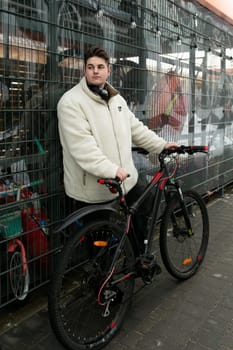 A young European man with a winter jacket took his bike outside.