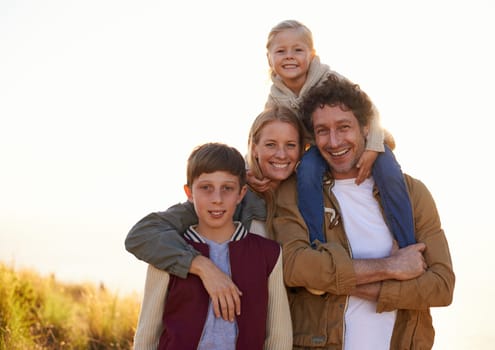 Family, portrait and smile with field, walk and sunrise for morning exercise and bond. Parents, children and countryside for health, wellness and outdoor adventure at sunset for holiday or vacation