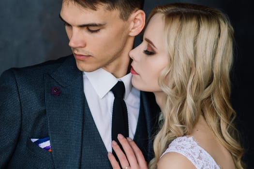 Cute wedding couple in the interior of a classic studio. They kiss and hug each other.