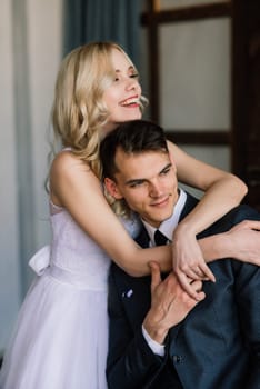 Cute wedding couple in the interior of a classic studio. They kiss and hug each other.