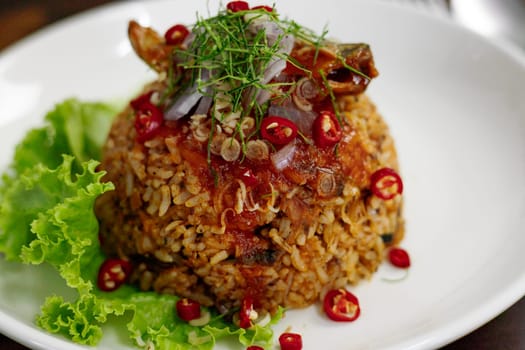 Thai food, Fried jasmine rice with canned fish mackerel in tomato sauce, topped with red chili, red onion, lettuce and kaffir lime leaves.