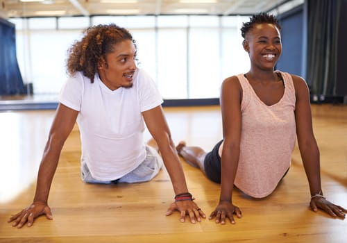 Dance, studio and people stretching on floor with happiness in class to start practice or rehearsal in academy. Healthy, students and exercise on ground for fitness with pilates or yoga in school.