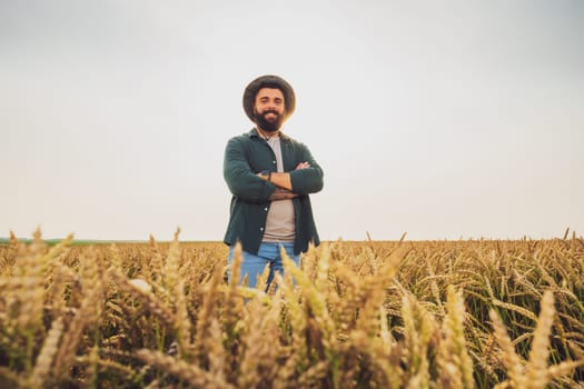 Portrait of farmer who is cultivating wheat. He is satisfied with good progress of plants. Agricultural occupation.