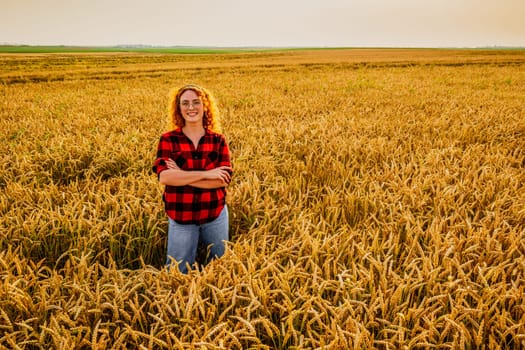 Portrait of female farmer who is cultivating wheat. She is satisfied with good progress of plants. Agricultural occupation.