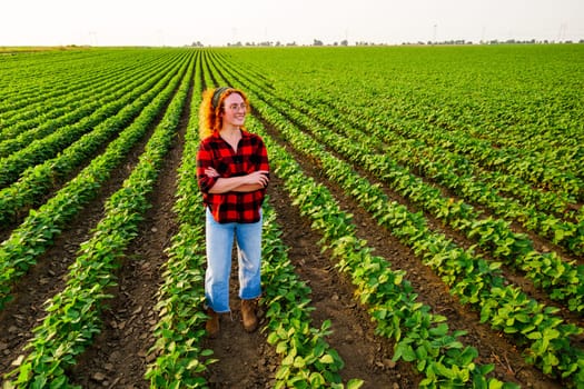 Portrait of female farmer who is cultivating soybean. She is satisfied with good progress of plants. Agricultural occupation.