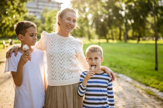 Portrait of happy single mother with her two sons in park on sunny day. Boys are eating ice cream.