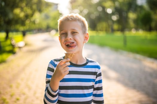 Portrait of happy boy who is standing in park and eating ice cream.