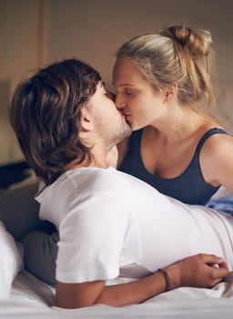 Love, kiss and couple on a bed with care, trust and support, security and bonding in their home together. Morning, romance and people embrace in a bedroom with intimacy, moment or fun in their house.