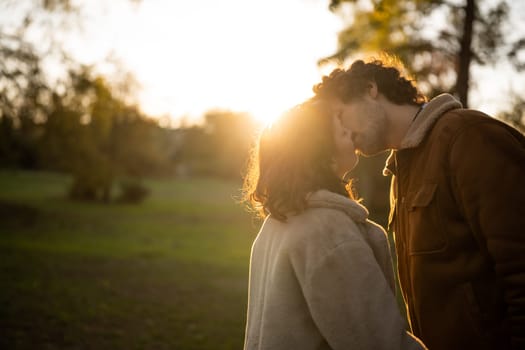 Portrait of happy loving couple in park in sunset. Couple in silhouette kissing.