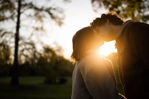 Portrait of happy loving couple in park in sunset. Couple in silhouette kissing.