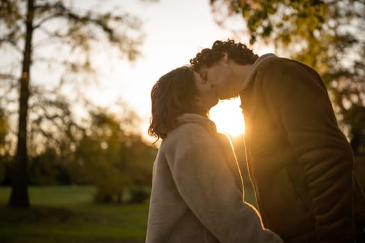 Portrait of happy loving couple in park in sunset. Couple in silhouette kissing.