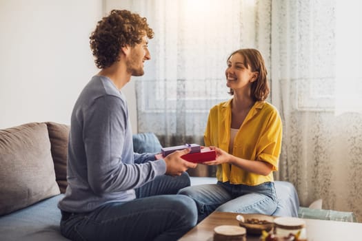 Portrait of young happy couple. Man is giving gift to his woman.