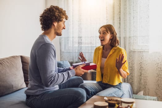 Portrait of young happy couple. Man is giving gift to his woman.