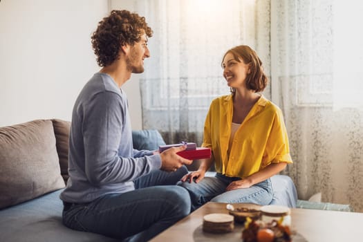 Portrait of young happy couple. Man is giving gift to his woman.