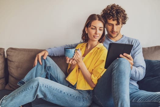 Portrait of young happy couple at home. They are relaxing at sofa.