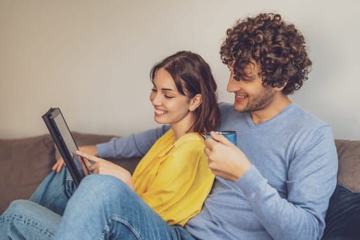 Portrait of young happy couple at home. They are relaxing at sofa.