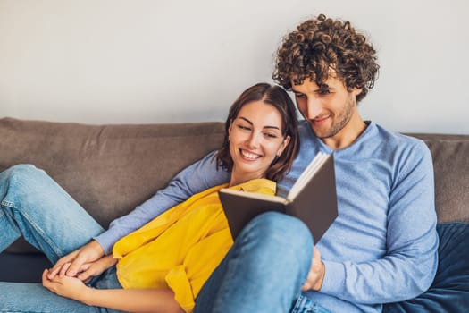 Portrait of young happy couple at home. They are relaxing at sofa.