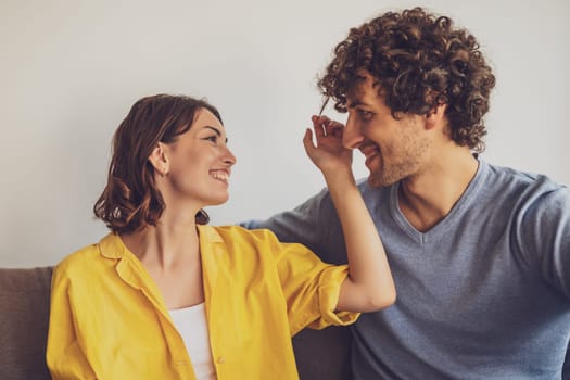 Portrait of young happy couple in love. Woman is playing with man's curly hair.