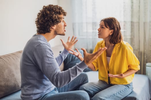 Man and woman are sitting at sofa and arguing. Relationship problems.