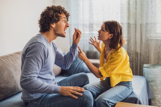 Man and woman are sitting at sofa and arguing. Relationship problems.