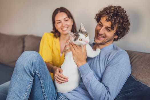 Portrait of young happy couple and their cat at home.