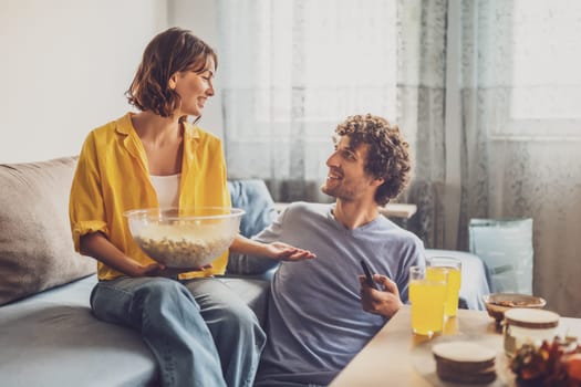 Portrait of young happy couple who is relaxing and watching TV at home.