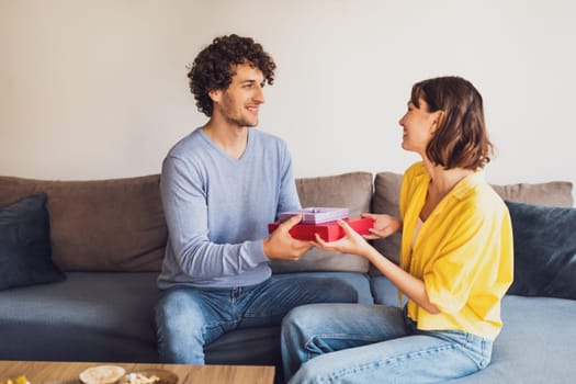 Portrait of young happy couple. Man is giving gift to his woman.