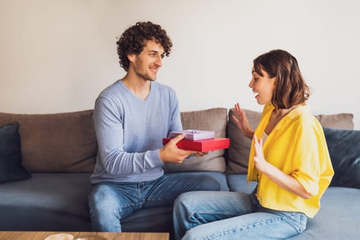 Portrait of young happy couple. Man is giving gift to his woman.