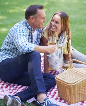 Couple, picnic and wine on travel in outdoor nature, love and romance in relationship on weekend. Alcohol, conversation and people on date in countryside, adventure and grass to relax on vacation.