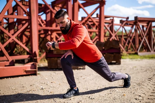 Adult man is exercising outdoor on sunny day. He is stretching his body.