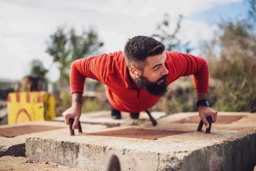 Young man is exercising outdoor. He is doing push-ups.