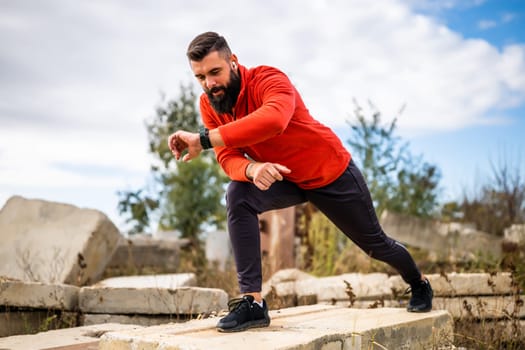 Adult man is exercising outdoor on sunny day. He is stretching his body.